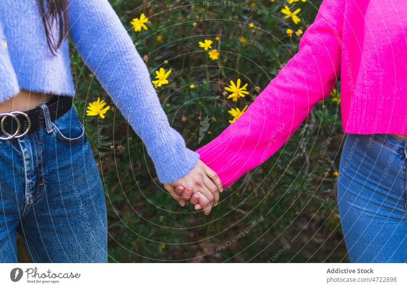 Unrecognizable women holding hands on street friend bush bonding relationship spend time friendship flower summer floral plant girlfriend city shrub together