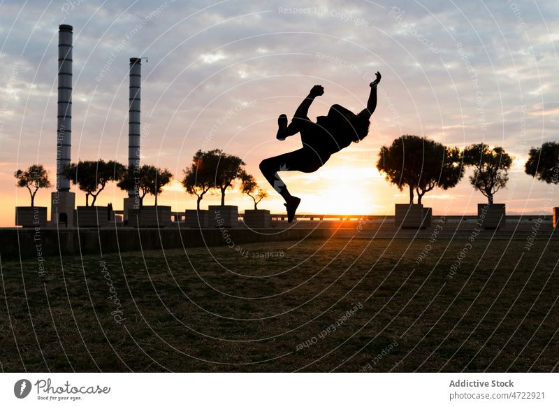 Jumping silhouette of active person over sunset man jump trick parkour above ground sundown freedom energy male guy unrecognizable anonymous faceless activity