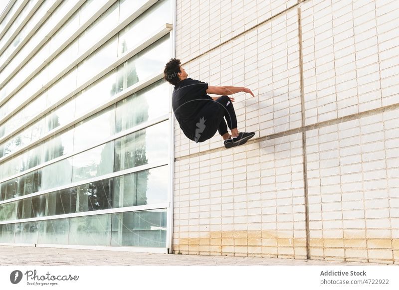 Sportive guy doing parkour on wall on street man jump stunt building above ground acrobatic energy perform male trick activity urban action active adrenalin
