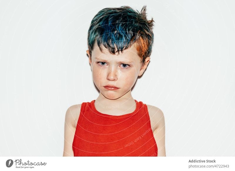 Offended boy with dyed hair kid naughty mischievous rebellious portrait disobedient unruly recalcitrant offended resentful serious room light colorful
