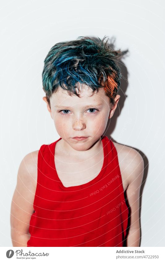Offended boy with dyed hair kid naughty mischievous rebellious portrait disobedient unruly recalcitrant offended resentful serious room light colorful