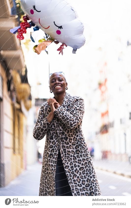 Cheerful black woman with cloud balloon on street raining playful city style carefree amusement pastime appearance african american short hair female lady urban