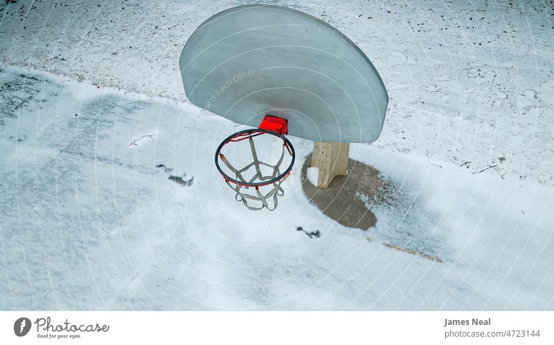A tall and long necked basketball court in winter score leisure games street frost goal backboard background orange snow city life sports venue net wisconsin