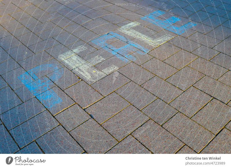 PEACE is written in blue and yellow with street chalk on the paving stones in the pedestrian zone Hope for peace Peace peace offer Peace Declaration Peace Wish