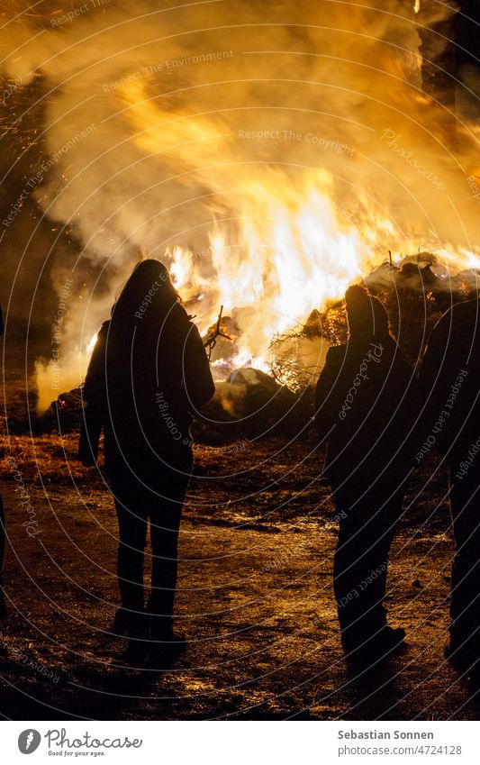 Silhouette of people standing in front of big fire Fire Night Flame Orange peril Light Yellow Red Heat Background lighting Black Smoke Europe Stand Dark Bonfire