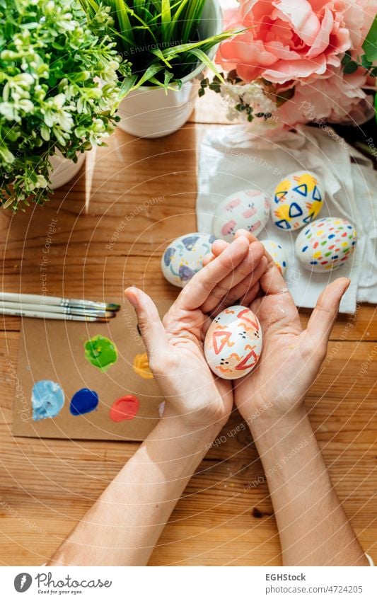 Female holding a modern easter egg. Brushes and paints with flowers and plants. Happy easter concept on a wooden background. hand celebration holiday brush
