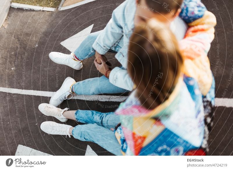 Top view of unrecognizable young couple sitting between the signs on the floor of a skate park unrecognized boyfriend girlfriend asphalt asphalted happy adult
