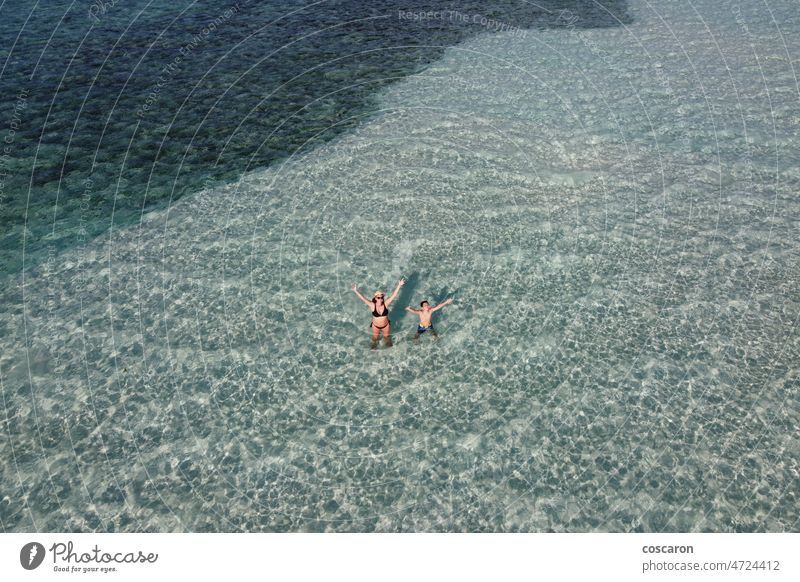 Mother and son waving from turquoise waters in the Maldive Islands above activity aerial angle authentic beach blue boy caucasian child exotic family greeting