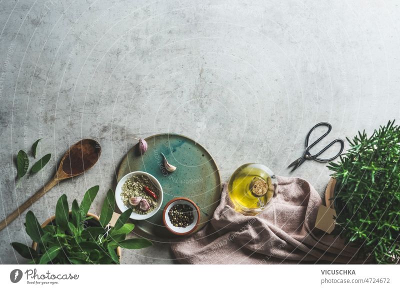 Food frame with plate, wooden spoon, potted kitchen herbs, olive oil, spices food potted herbs garlic kitchen cloth concrete table cooking home flavorful