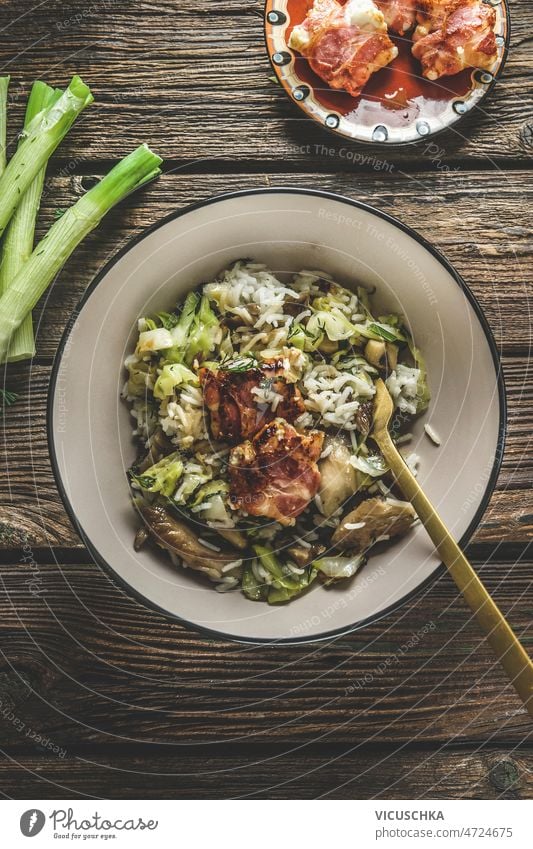 Homemade rice dish with leek and meat in bowl on rustic wooden kitchen table homemade fork vegetable fried bacon delicious healthy food ready to eat top view