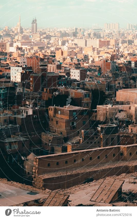 View of numerous buildings and rooftops of Cairo city, multi milion capital city filled with little houses and huge apartment blocks. Orange sandy mood in winter time in cairo