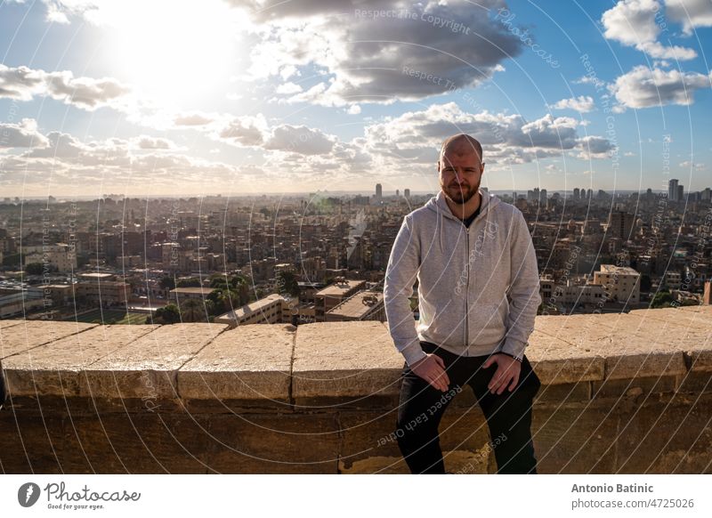 Man sitting on a ledge in Cairo, view of the city and the pyramids in the distance cairo travel egypt luxor ancient Luxor Giza Pyramid architecture Landscape