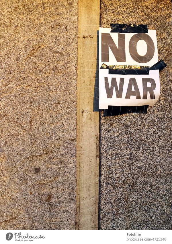 "NO WAR" is written on the white sheets taped to the wall with black tape. writing Text Letters (alphabet) Word Characters Typography Wall (building) Facade