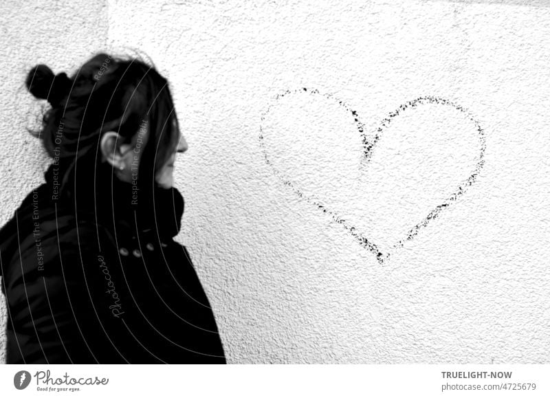Approach: warm wrapped woman, hair tied up, looking at heart love message on white house wall Woman Profile long hairs Coat Scarf Heart Graffiti sketch outline