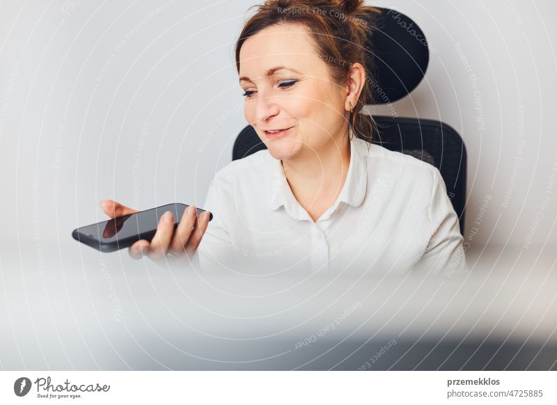 Businesswoman talking on mobile phone using speaker mode. Woman recording audio message using voice assistance and recognition function on smartphone business