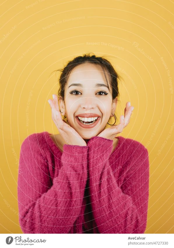 Young woman on pink smiling while touching face to camera. Young woman attitude. Yellow tone color background, expression of normal people. Mockup concept with people