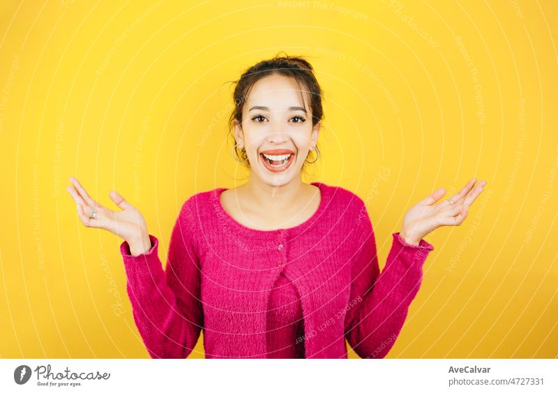 Young woman on pink shirt not knowing what to do raising hands. Young woman attitude. Yellow tone color background, expression of normal people. Mockup concept with people