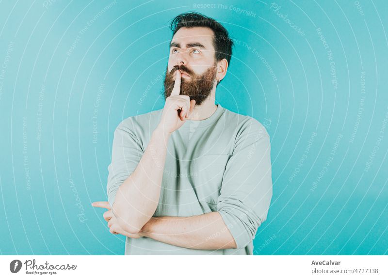 Handsome hipster bearded thinking something and trying to find a solution. Young man attitude funny. Blue tone color background, expression of normal people. Mockup concept with people