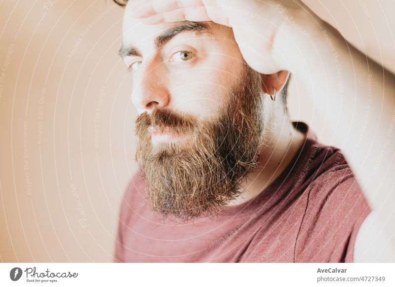 Close up portrait of a young handsome hipster man taking a look suspicious directly to camera. Inspecting something with distrust.Soft tone color background, expression of normal people.