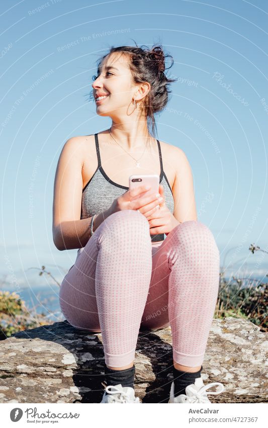Young woman outdoors on sport clothes checking her smart phone after training. Carefree, positive and freedom concept. Healthy lifestyle doing exercise outdoors. Super smile with confident attitude