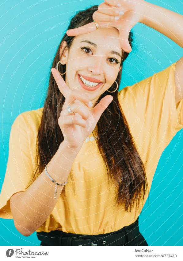 Young woman doing the taking a snap gesture to camera while smiling happy. Blue tone color background, expression of normal people. Mockup concept with people