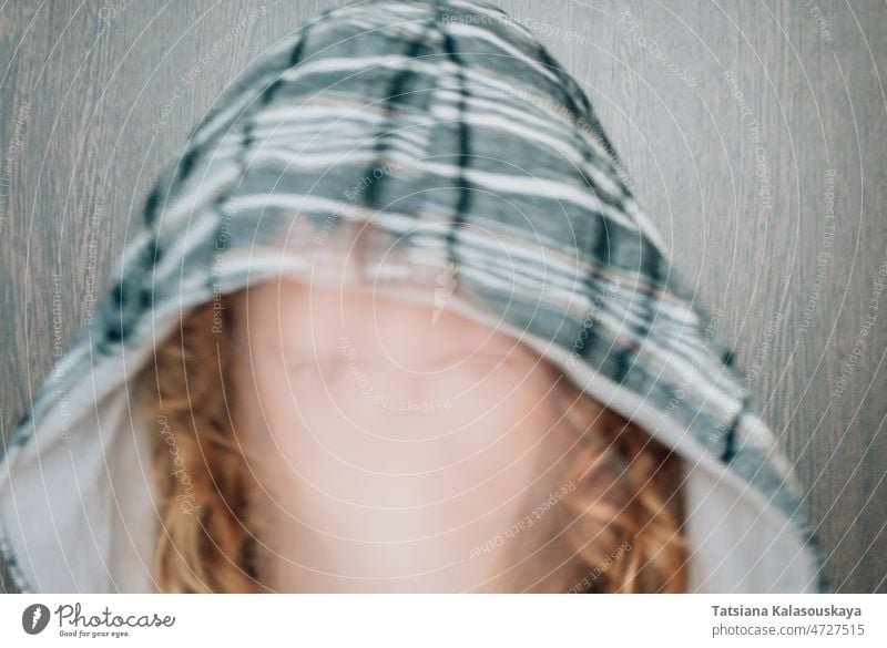Blurred focus in the face of a woman in a hood red hair head gaze intent looking at the camera blur movement blurred focus gray cage Looking at camera eyes
