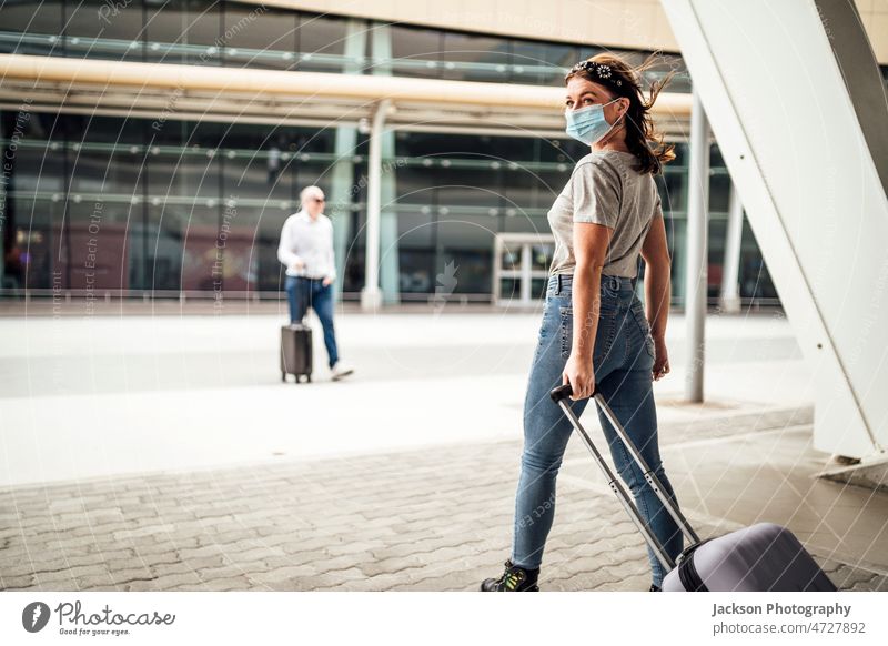 A young woman wearing mask walking with the suitcase to the airport traveller luggage covid pandemic arrive technology coronavirus commuter departure leave