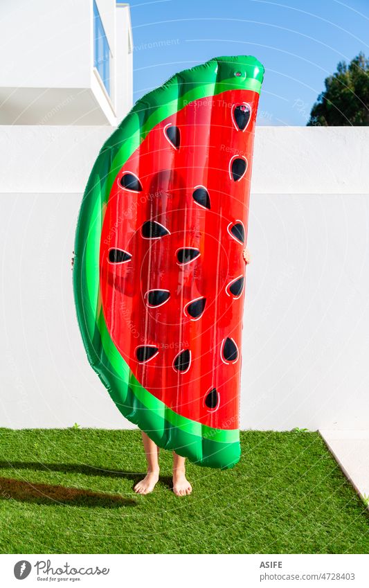 Teen girl holding a watermelon shaped inflatable matress near the swimming pool mattress summer float child vacation fun funny house home grass young leisure