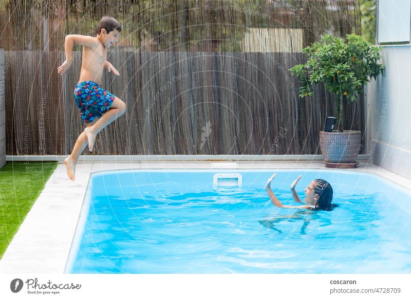 Two kids playing in a swimming pool action beach blue child childhood children playing danger dive exciting family fun girl happiness happy holiday hotel jump
