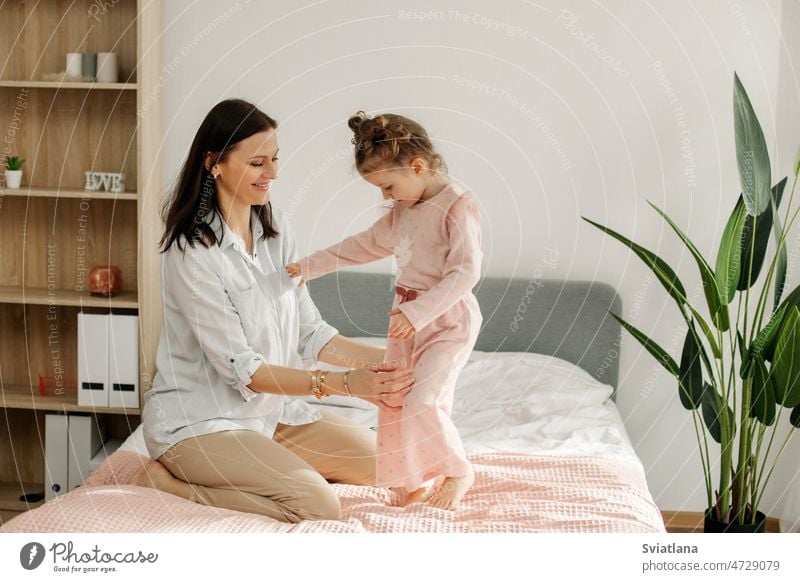 A young mother plays with her baby in the bedroom. Happy loving family. mom playing fun girl child happy portrait funny happiness healthy indoors joy joyful
