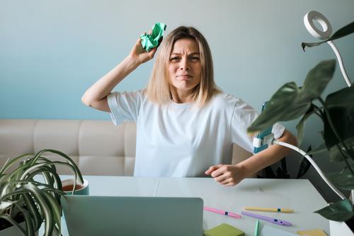 Woman angrily throws a crumpled piece of paper. Woman freelancer in stress. No ideas. Emotional burnout at work. Trouble at work from home online job woman
