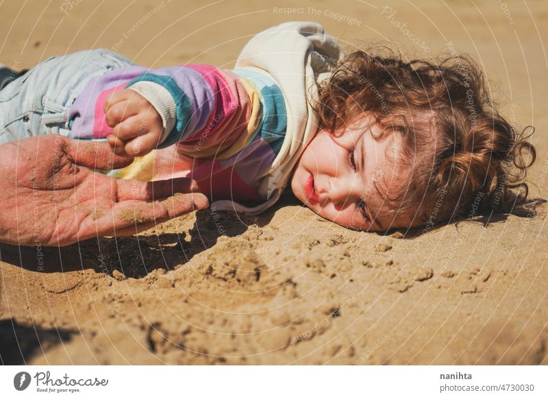 Little girl playing on the sand with her dad beach family joy playful happy happiness toddler father single exercise share care caring love together