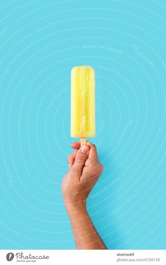Hand holding a lemon popsicle blue cold colorful cool cream dessert flavor food fresh frosty frozen fruit hand homemade ice ice cream icecream iced juice lolly
