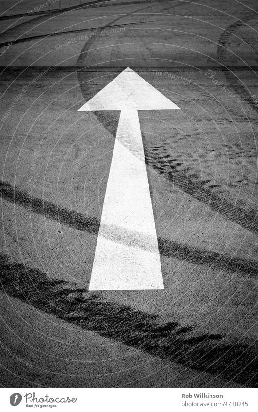 White arrow on an empty car park tarmac ahead arrow symbol asphalt black concept decision direction directional directional sign forward future goal guidance