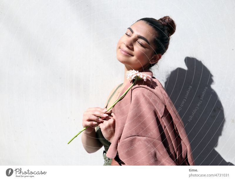 Woman with flower and coat Flower Coat Shadow Smiling Wall (building) Chignon Dark-haired Stand stop be comfortable fortunate contented