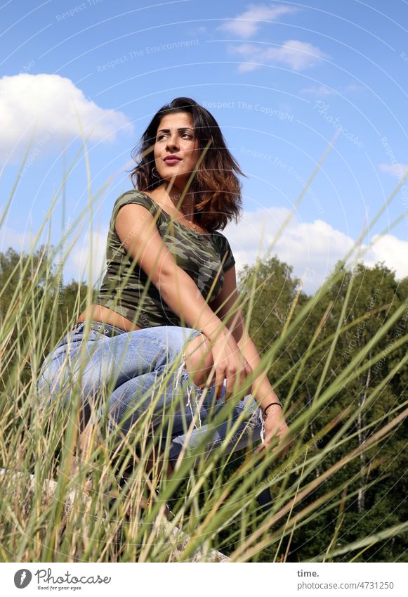 Woman, ready to jump T-shirt Long-haired Feminine Dark-haired Nature sunny trees Crouch Sit Grass Half-profile jeans