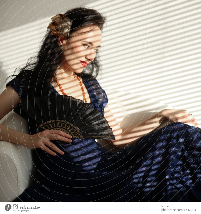 Woman with fan Elegant Dress Dark-haired Jewellery Colour Guide Armchair Sit portrait Profile look Long-haired Curl Sunlight sunny Shadow Strip of light