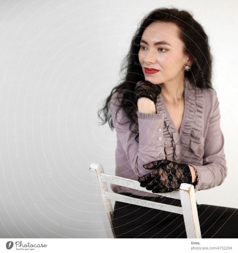 Sitting woman with gloves Woman Feminine Elegant Chair Shirt Frill shirt Gloves Dark-haired Half-profile Forward Long-haired