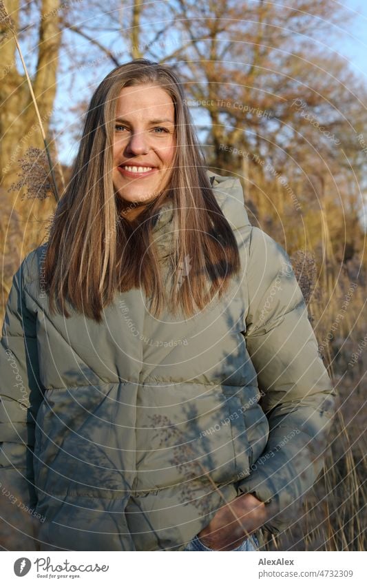 Tall blonde woman with long hair in warm light green jacket smiling very close to camera outside Woman Young woman pretty Blonde Long-haired long hairs portrait