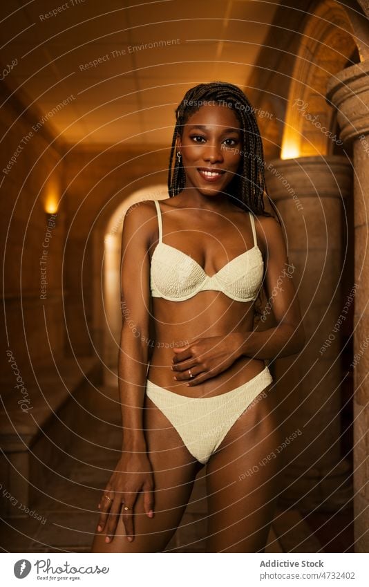 African American woman in bikini standing in spa swimsuit vacation center fit body care hotel resort female ethnic black african american wellness swimwear