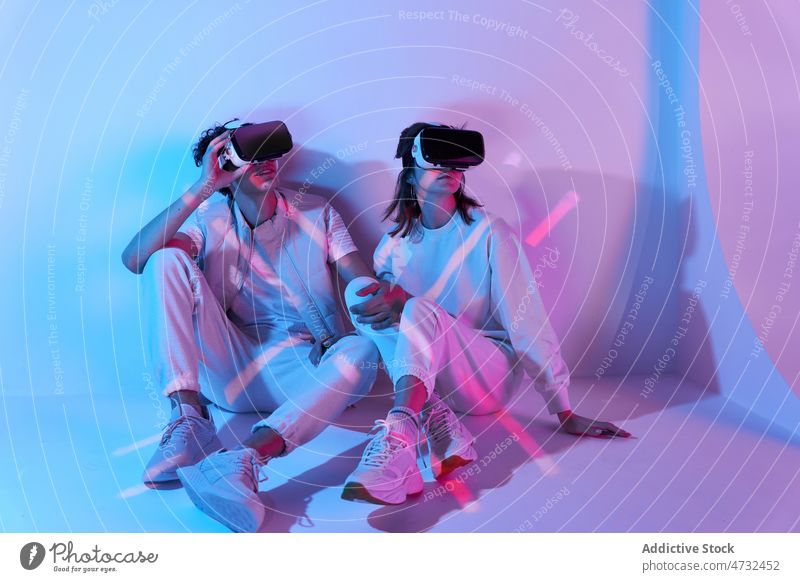 Couple in VR headset sitting near wall couple vr virtual reality cyberspace future augmented reality interactive technology explore goggles futuristic studio