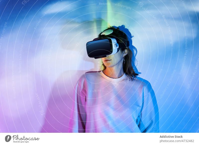 Woman in VR headset near wall with glowing lights woman vr virtual reality cyberspace future augmented reality interactive explore technology goggles futuristic