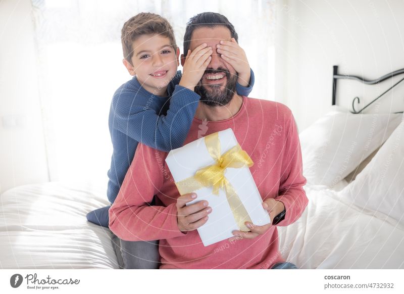 Son closing eyes to his father and giving a gift affection beard birthday box boy caucasian celebrate celebrating cheerful child childhood cute dad daddy family