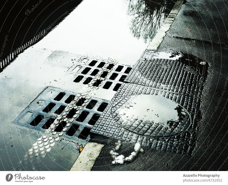 Water flowing into the sewer manhole. Wet road with sewer hatches. abstract asphalt avenue background bright sunlight circle city concrete cover dirty drain