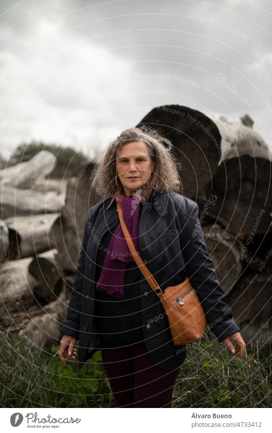 A woman, 60, with gray hair, standing, enjoys a walk in the countryside, in spring, in a rural area of the Campo de Borja region, Zaragoza province, Aragon, Spain