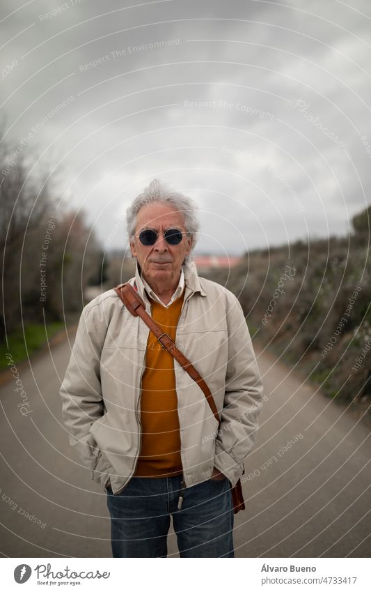 A man, with gray hair, standing, enjoys a walk in the countryside, in spring, in a rural area of the Campo de Borja region, Zaragoza province, Aragon, Spain