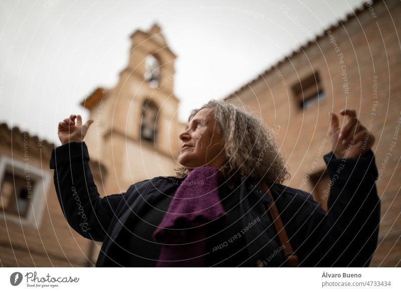 A woman with gray hair enjoys the architecture and the view from the bell tower of the church of the Visitation in Malejan during a rural tourism getaway in Aragon, Spain