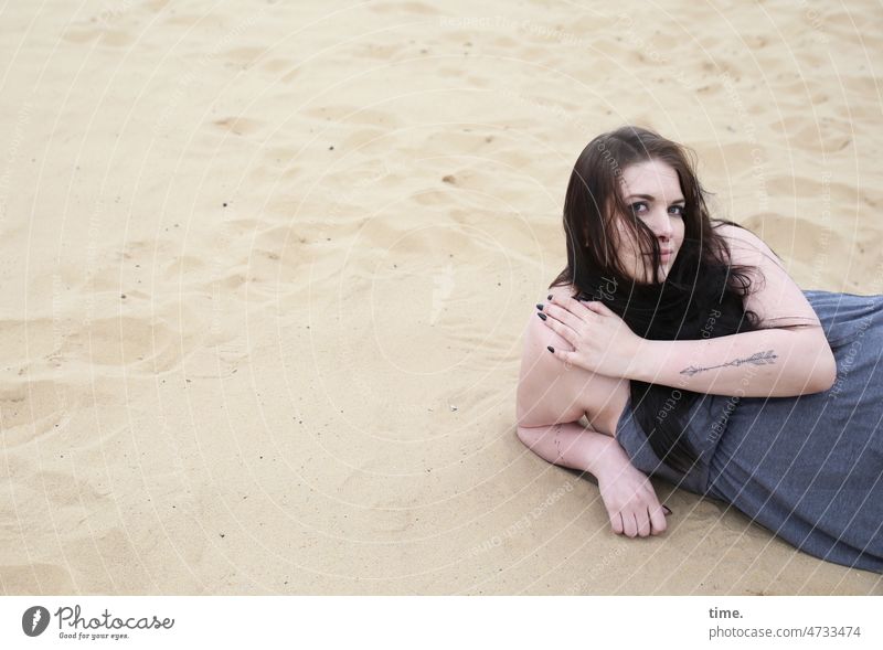 lying woman in sand Lie look Woman Dress Feminine Long-haired Dark-haired Tattoo Sand Rest on Support Skeptical