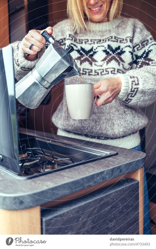 Woman serving coffee with coffee maker in camper van woman unrecognizable motorhome italian coffee maker smiling cup wool sweater detail smile
