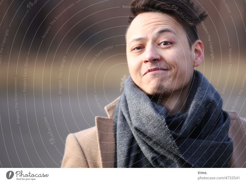 Man with scarf Short-haired Coat Scarf Smiling Impish Looking into the camera sunny